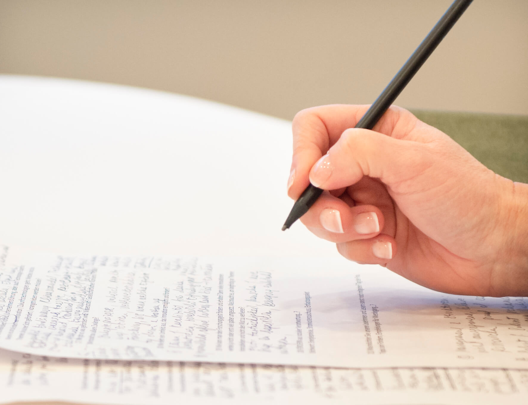 Eine Hand die einen Stift hält und ansetzt zum Schreiben auf einem Blatt Papier